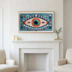 Folk art mystic eye art above a white fireplace with candles and eucalyptus on the mantel