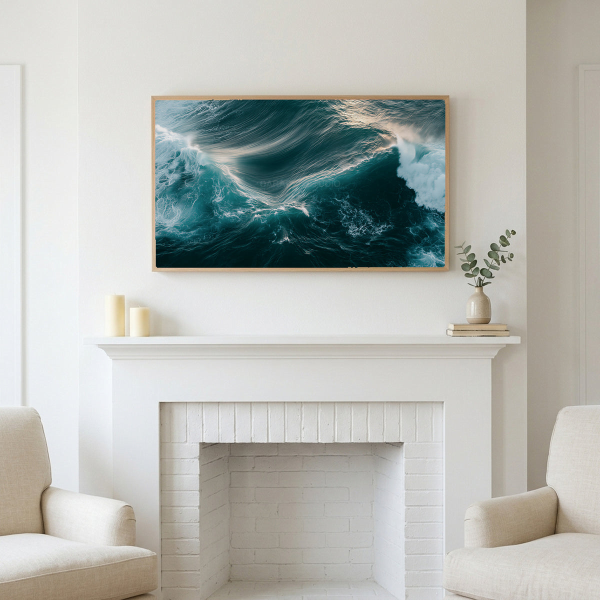 Aerial ocean waves art above a white fireplace with candles and eucalyptus on the mantel