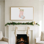 Cat stocking art on a TV above a white fireplace with a pine garland and cream stockings
