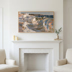 Crashing ocean waves art above a white fireplace with candles and eucalyptus on the mantel