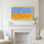 Cross on a golden field art above a white fireplace with candles and eucalyptus on the mantel