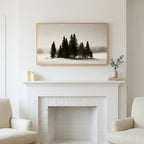 Snowy pine trees art above a white fireplace with candles and eucalyptus on the mantel