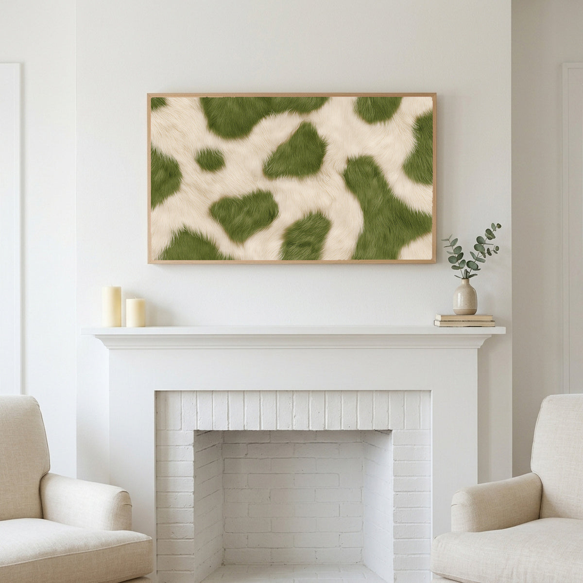 Olive cowhide art above a white fireplace with candles and eucalyptus on the mantel