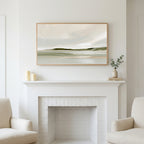 Misty sage shoreline art above a white fireplace with candles and eucalyptus on the mantel
