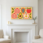 Colorful fruit halves art above a white fireplace with candles and eucalyptus on the mantel