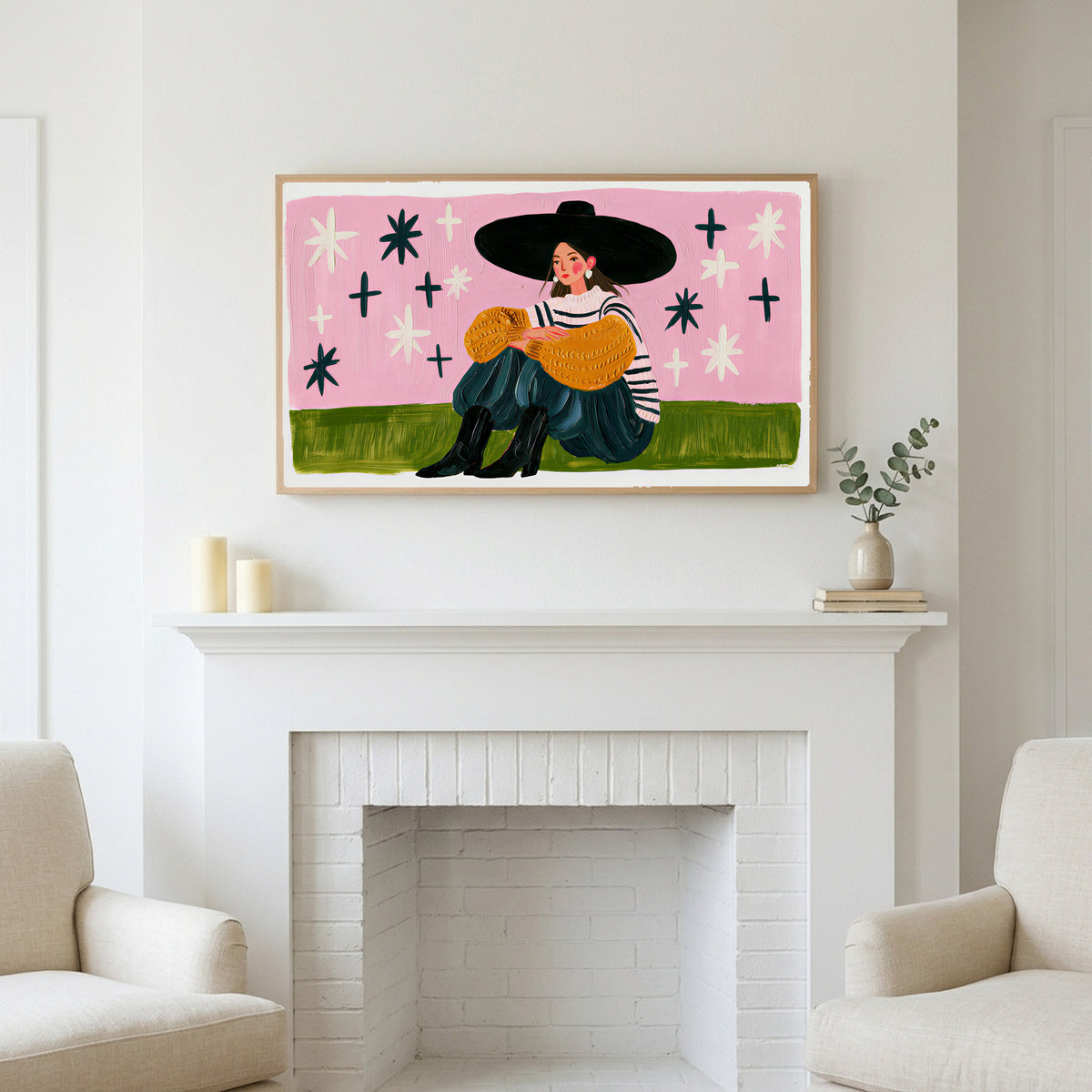 Woman in a big hat art above a white fireplace with candles and eucalyptus on the mantel