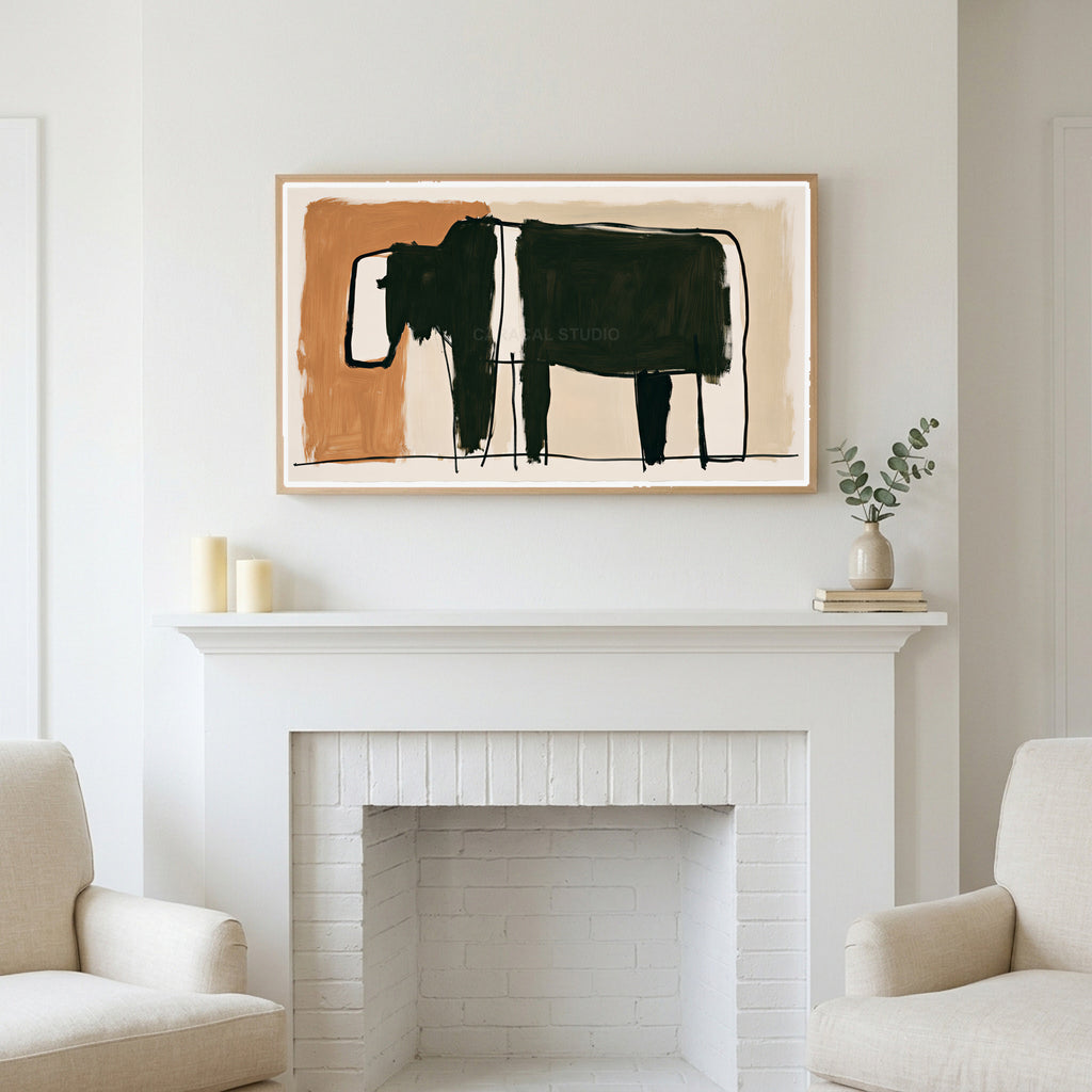 Minimalist black cow art above a white fireplace with candles and eucalyptus on the mantel