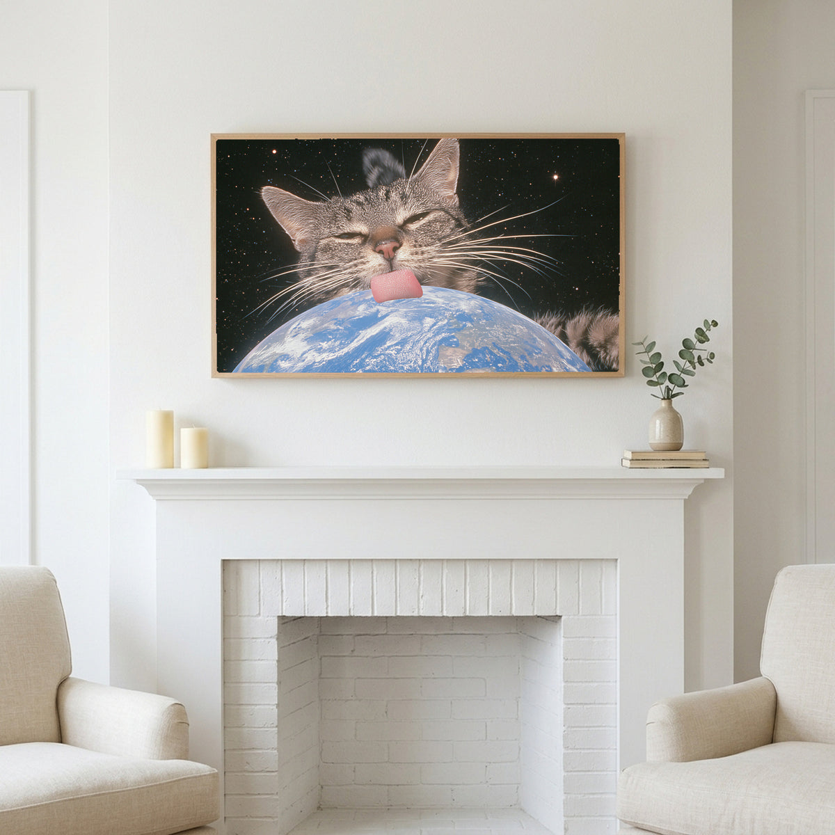 Space cat art above a white fireplace with candles and eucalyptus on the mantel