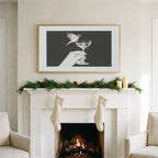 Bird and champagne glass art on a TV above a white fireplace with a pine garland and cream stockings