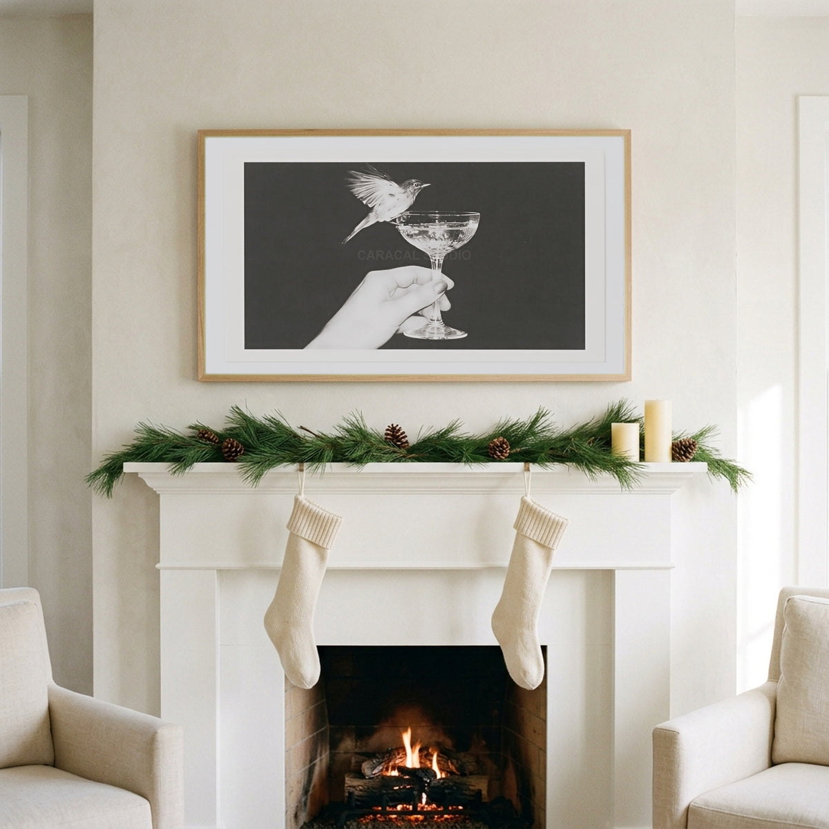 Bird and champagne glass art on a TV above a white fireplace with a pine garland and cream stockings