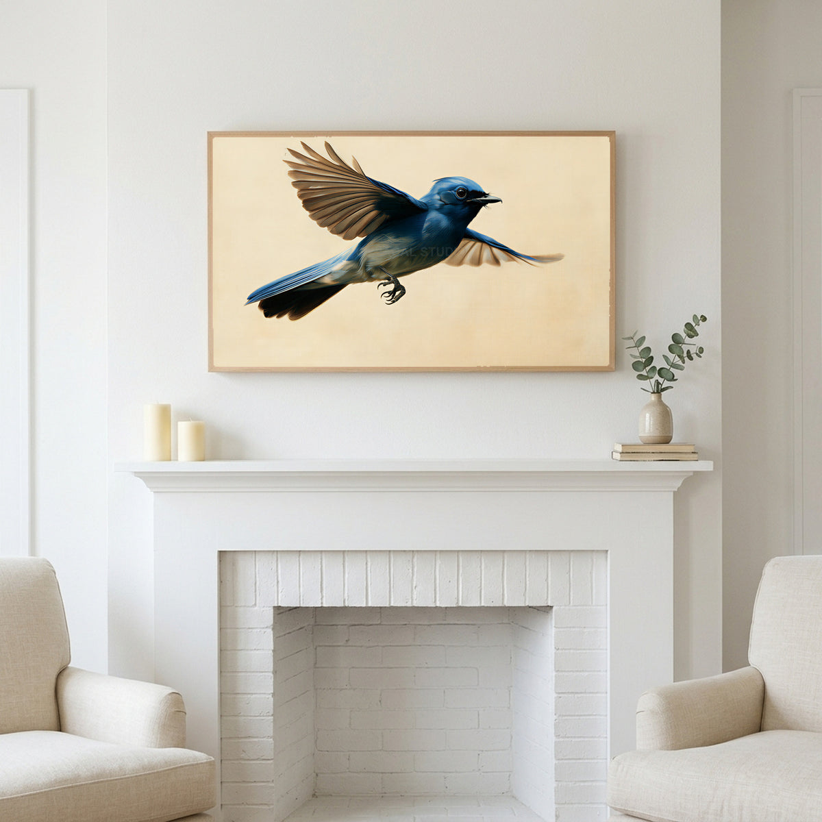 Blue flycatcher art above a white fireplace with candles and eucalyptus on the mantel