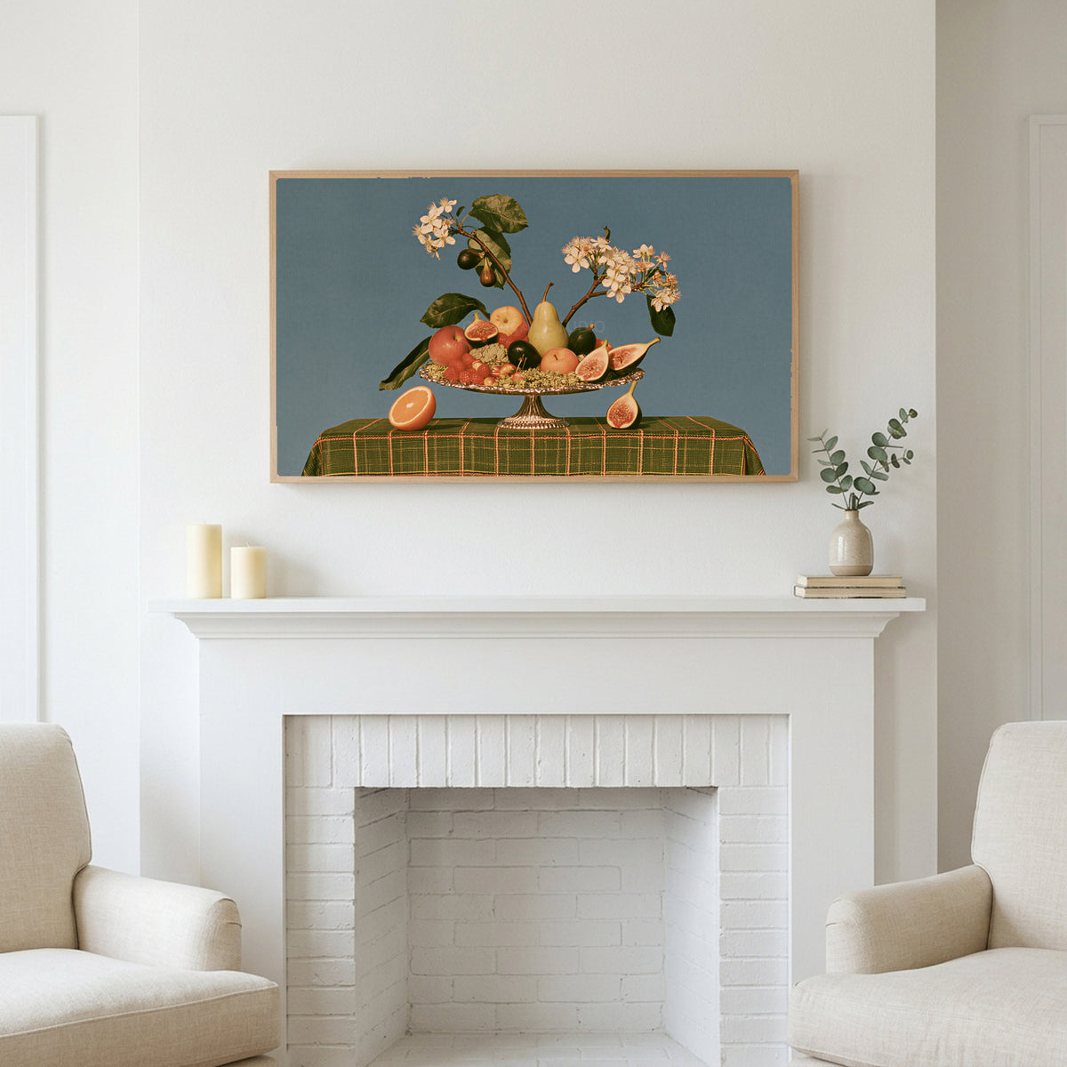 Fruit still life art above a white fireplace with candles and eucalyptus on the mantel