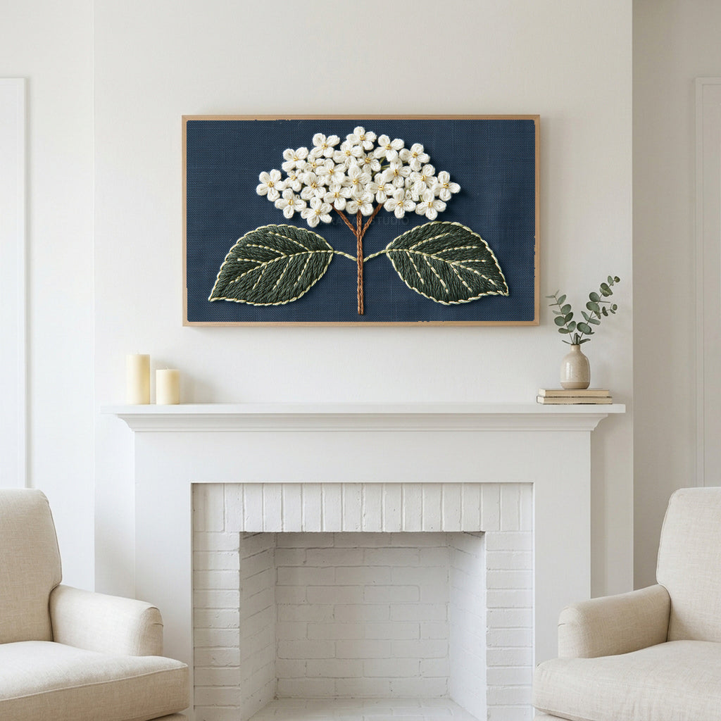 Embroidered hydrangea art above a white fireplace with candles and eucalyptus on the mantel