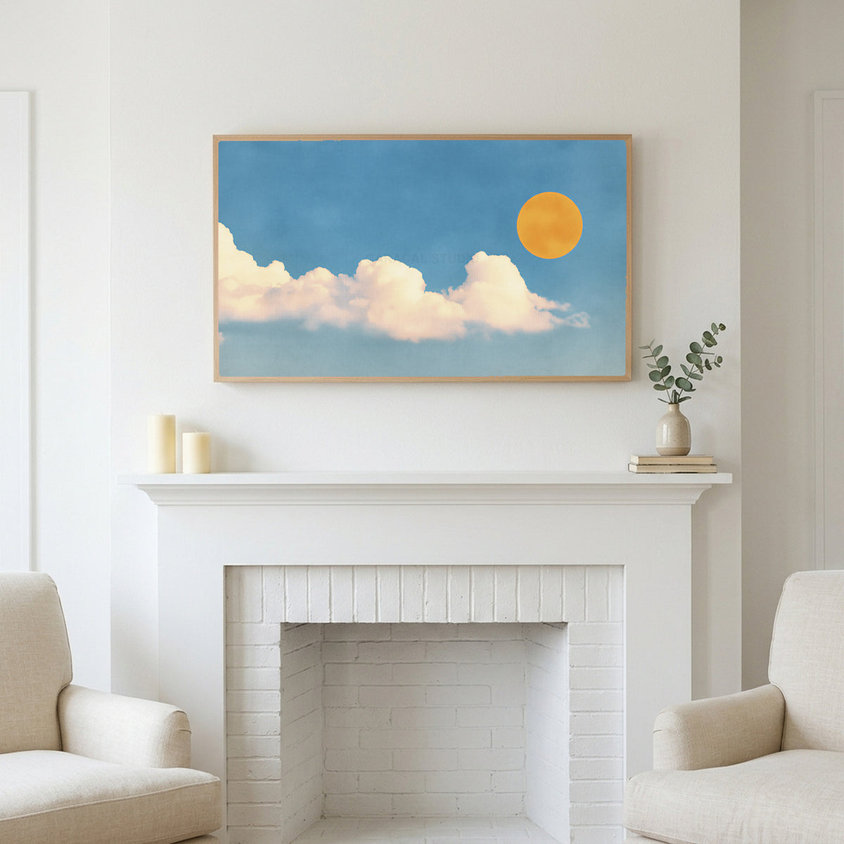 Sun and clouds art above a white fireplace with candles and eucalyptus on the mantel