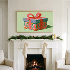 Gift box art on a TV above a white fireplace with a pine garland and cream stockings