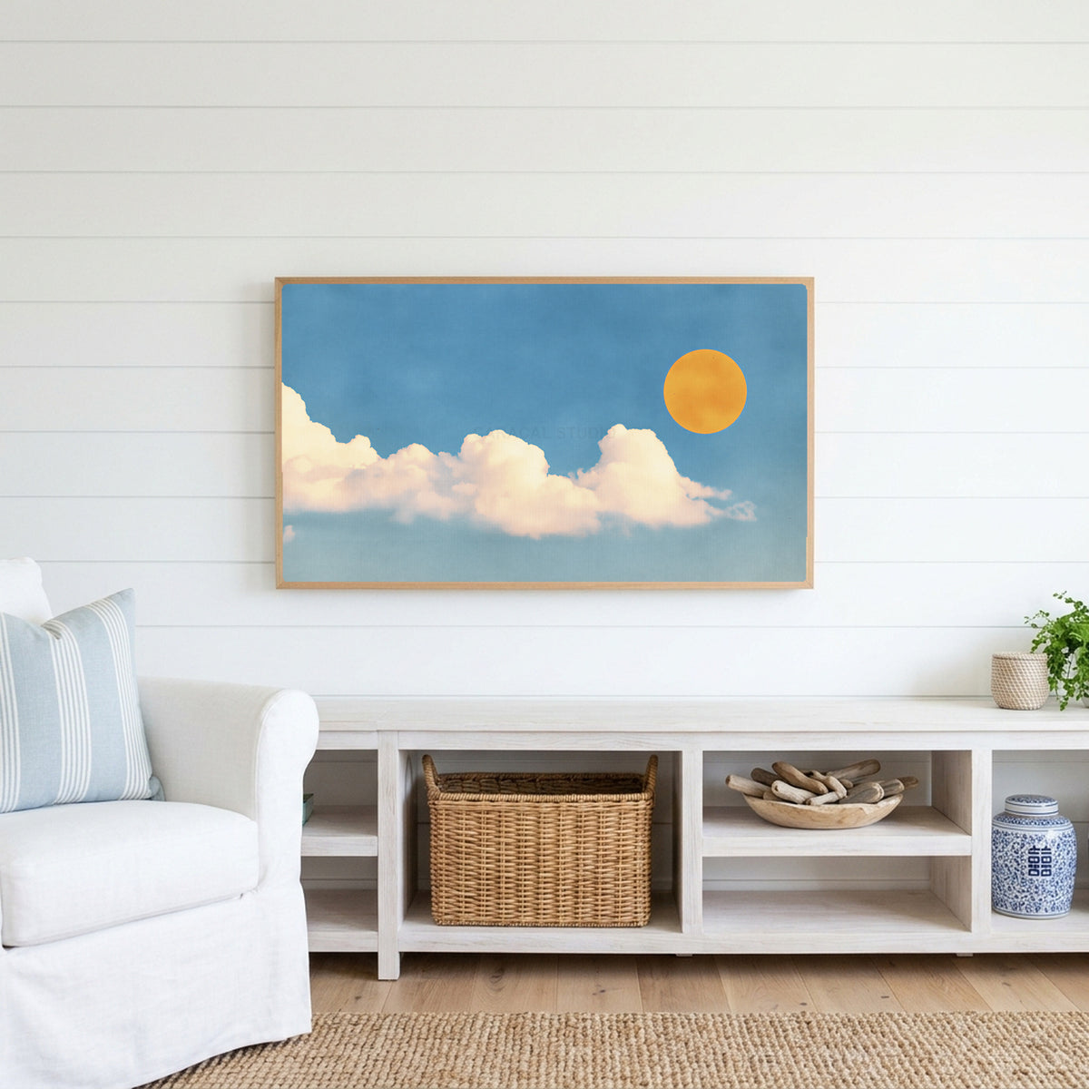 Sun and clouds Frame TV art above a white console with a rattan basket in a coastal living room