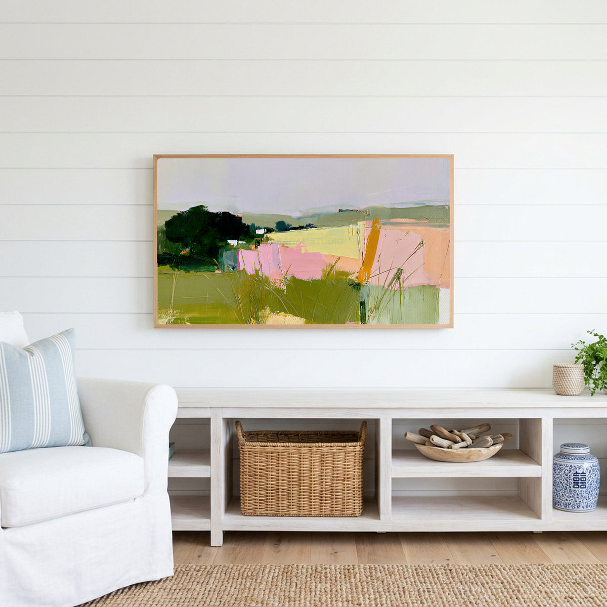 Abstract countryside Frame TV art above a white console with a rattan basket in a coastal living room