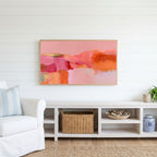 Pink abstract color blocks Frame TV art above a white console with a rattan basket in a coastal living room