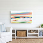 Abstract sunset hills Frame TV art above a white console with a rattan basket in a coastal living room