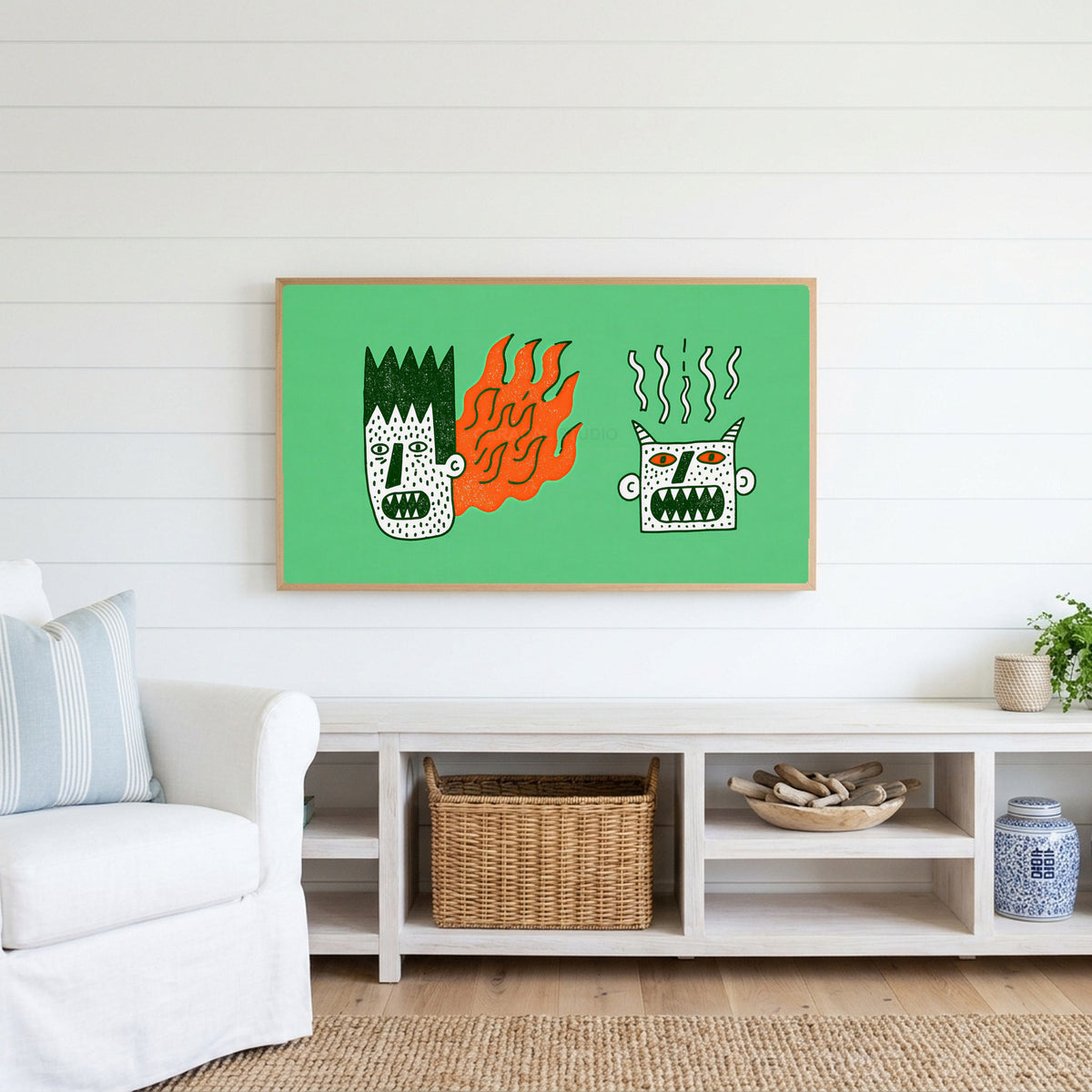 Grumpy doodle faces Frame TV art above a white console with a rattan basket in a coastal living room