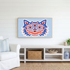 Three-eyed wolf Frame TV art above a white console with a rattan basket in a coastal living room