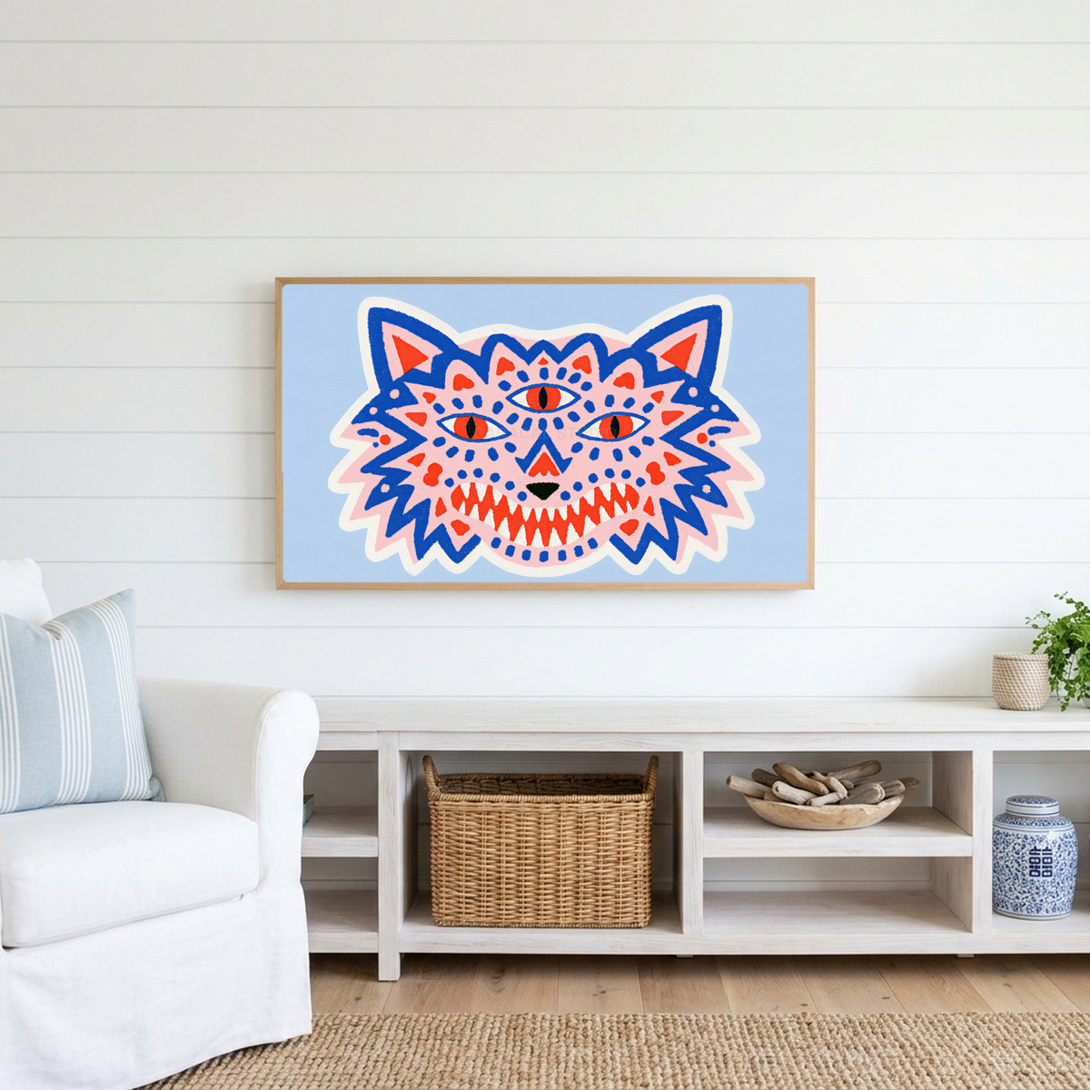 Three-eyed wolf Frame TV art above a white console with a rattan basket in a coastal living room