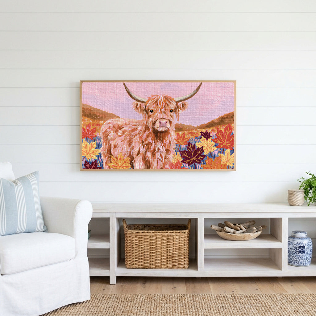 Highland cow in fall leaves Frame TV art above a white console with a rattan basket in a coastal living room