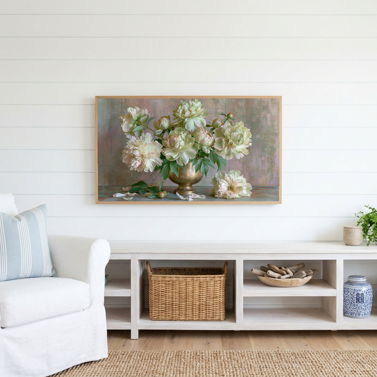 Peonies in a brass urn Frame TV art above a white console with a rattan basket in a coastal living room