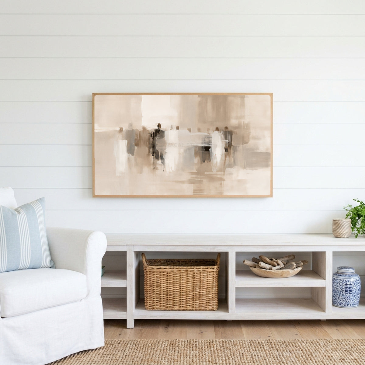 Neutral abstract figures Frame TV art above a white console with a rattan basket in a coastal living room