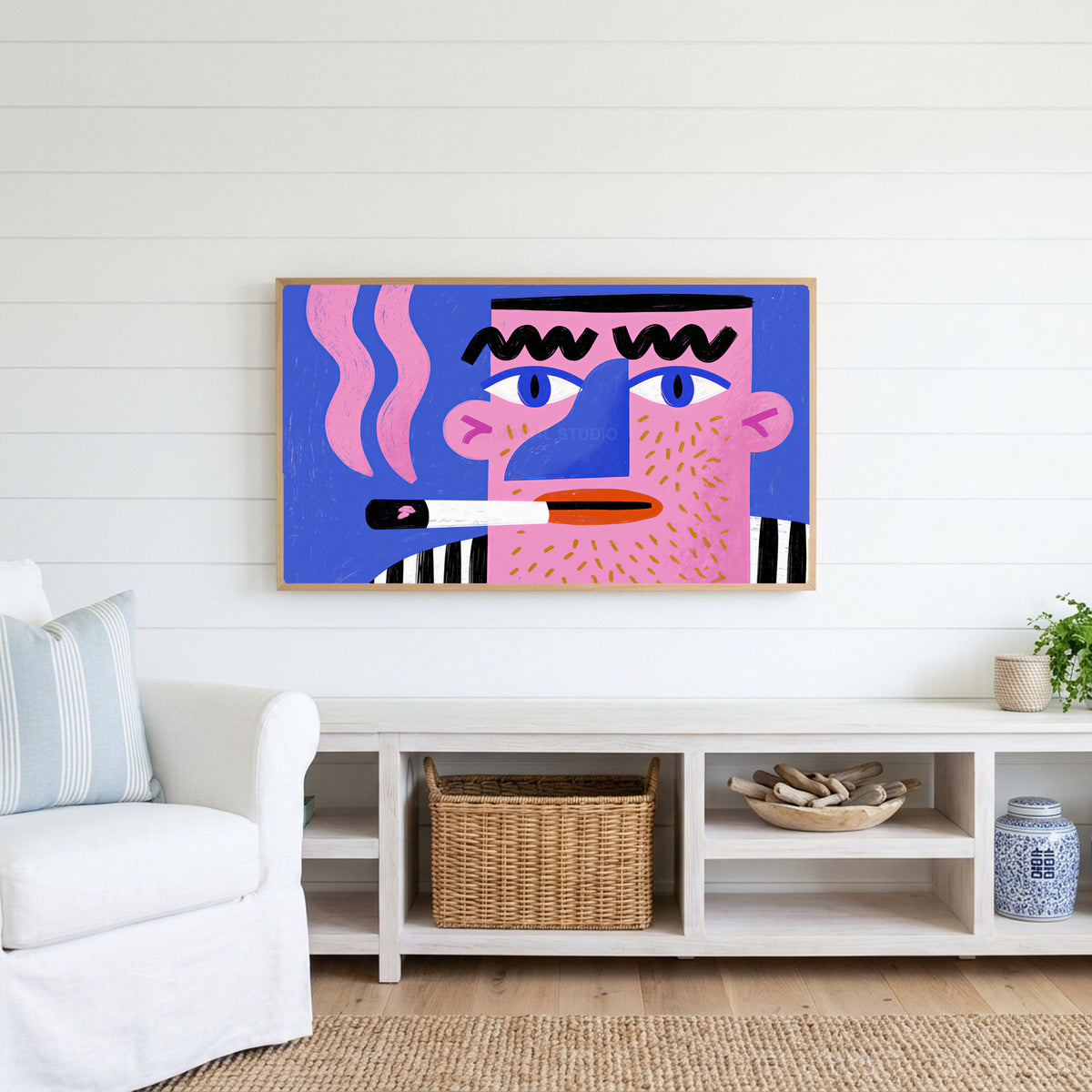 Pop art face Frame TV art above a white console with a rattan basket in a coastal living room