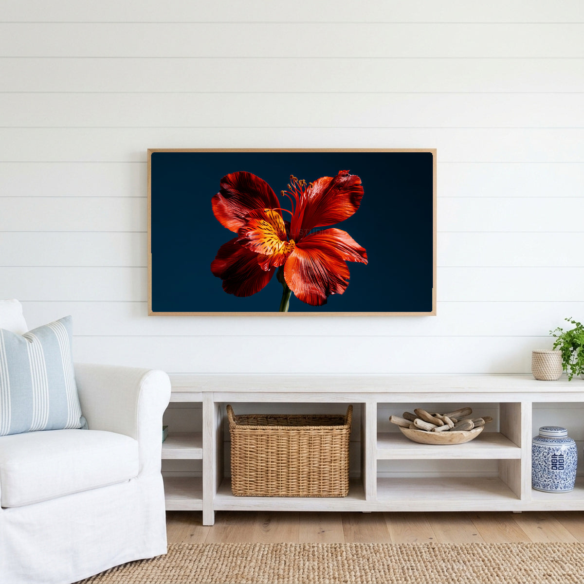 Red lily on navy Frame TV art above a white console with a rattan basket in a coastal living room