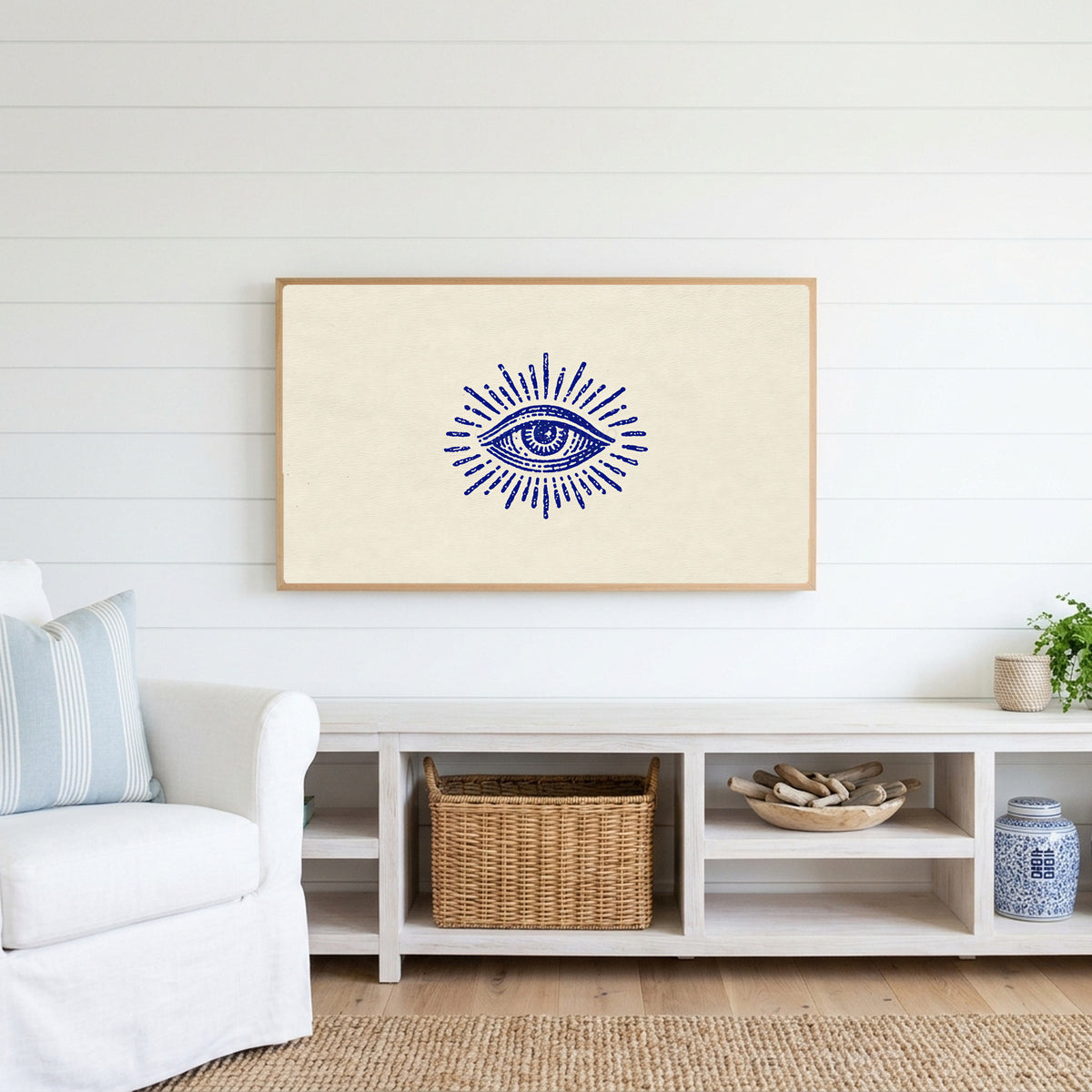 Mystic eye Frame TV art above a white console with a rattan basket in a coastal living room