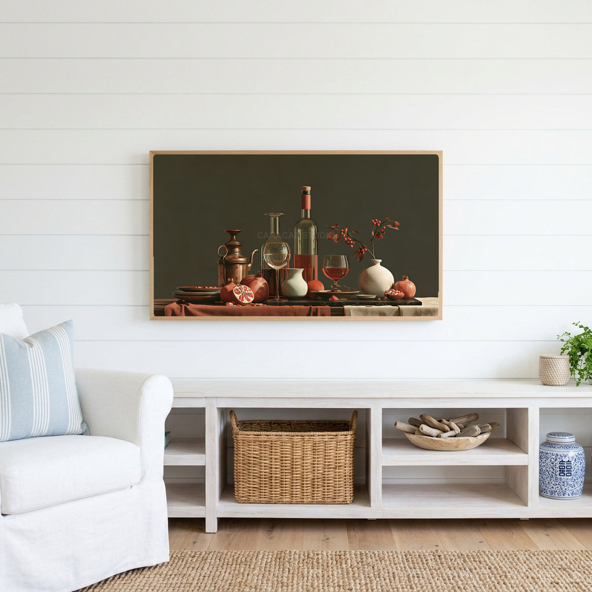 Wine and pomegranates still life Frame TV art above a white console with a rattan basket in a coastal living room