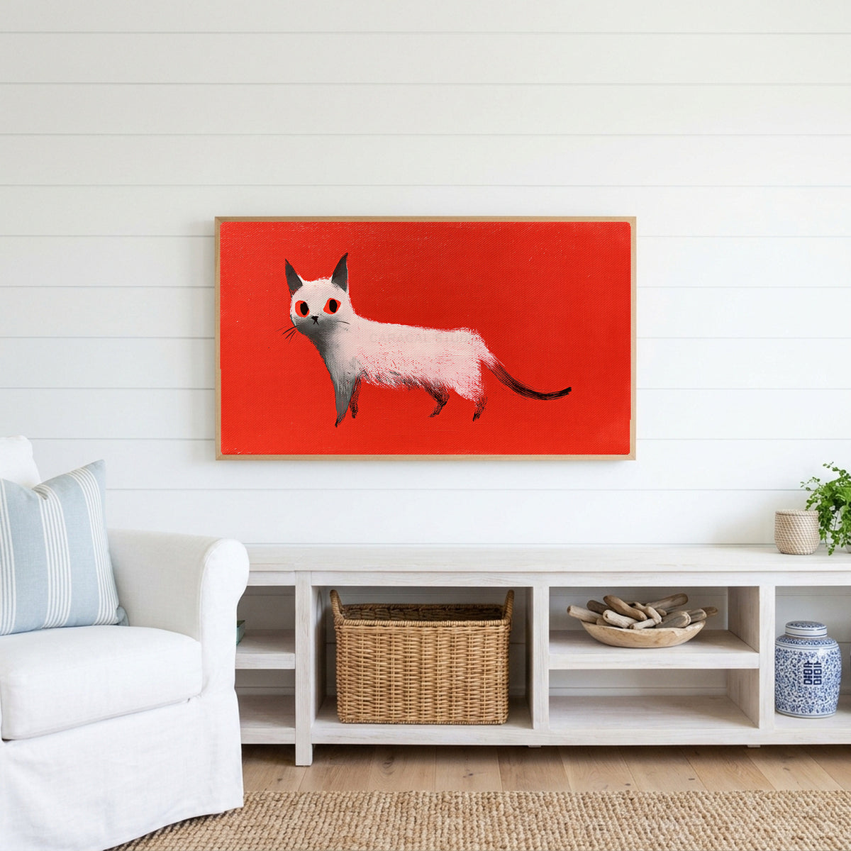White cat Frame TV art above a white console with a rattan basket in a coastal living room