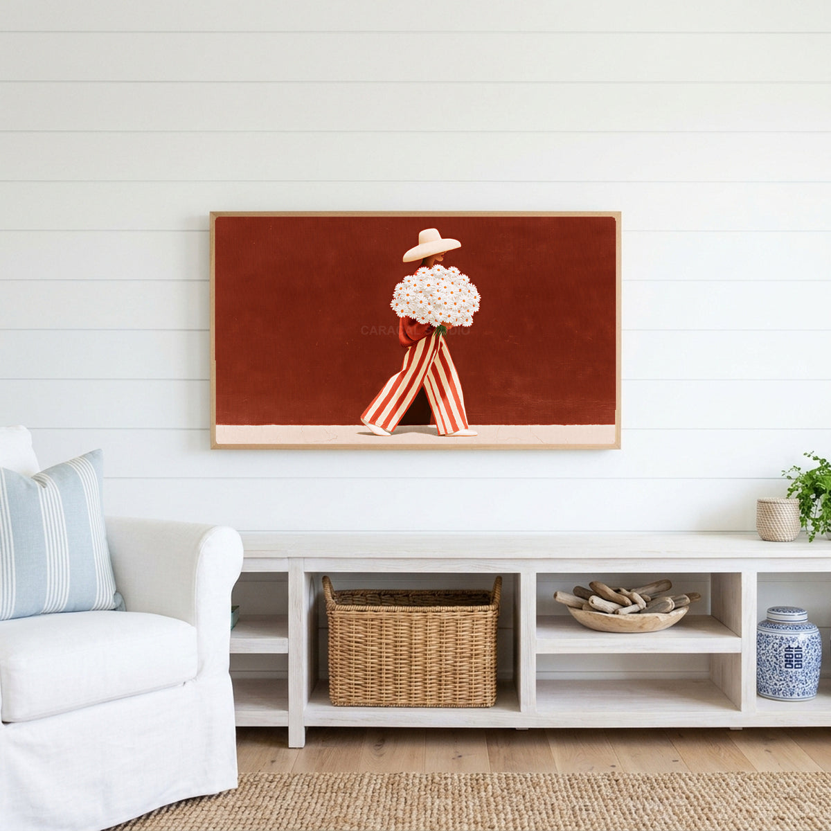 Figure with a daisy bouquet Frame TV art above a white console with a rattan basket in a coastal living room