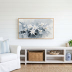 White flower Frame TV art above a white console with a rattan basket in a coastal living room