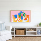 Breakfast table with flowers Frame TV art above a white console with a rattan basket in a coastal living room