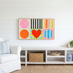 Colorful shapes and heart Frame TV art above a white console with a rattan basket in a coastal living room