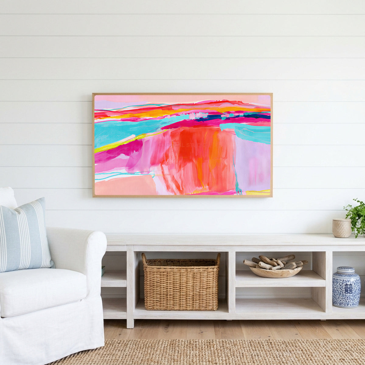 Pink abstract horizon Frame TV art above a white console with a rattan basket in a coastal living room