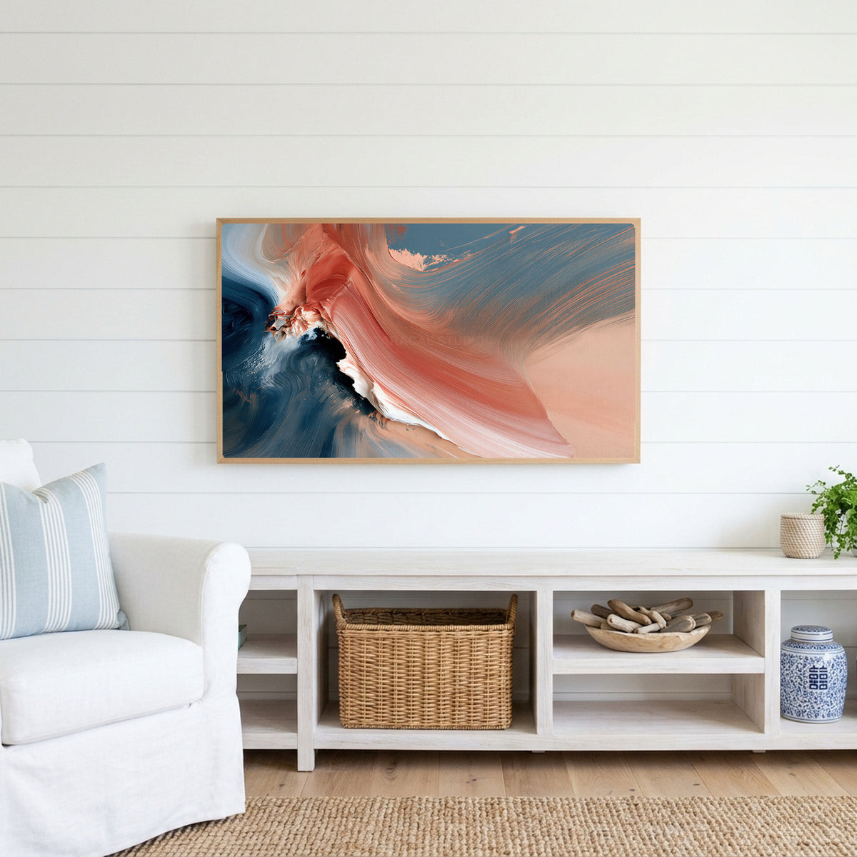 Coral and navy abstract Frame TV art above a white console with a rattan basket in a coastal living room