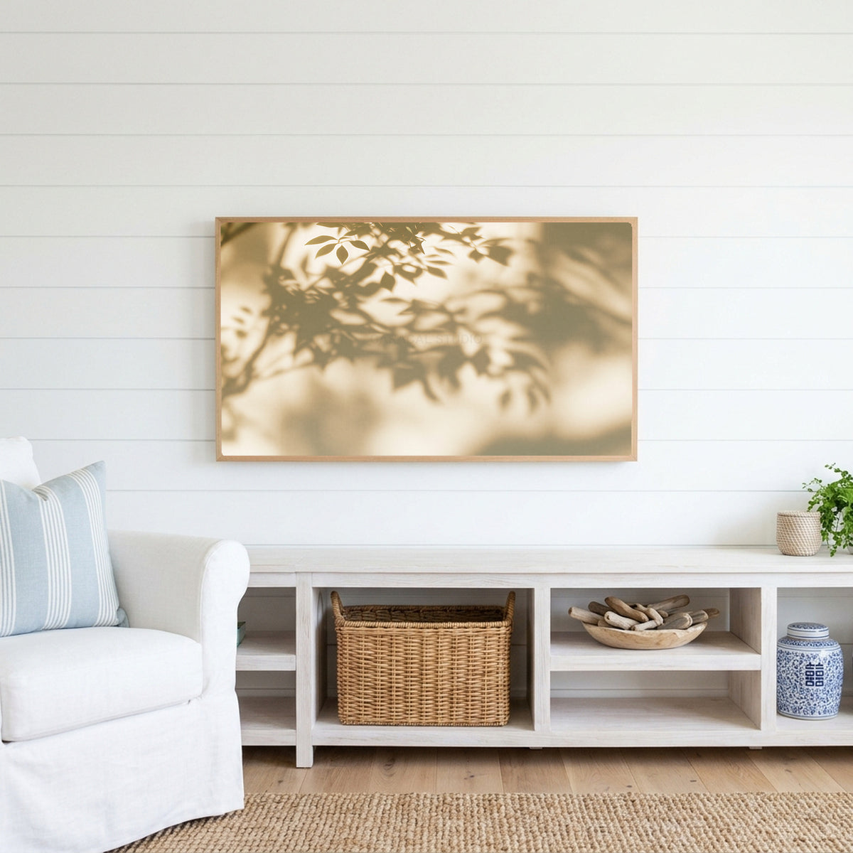 Leaf shadow Frame TV art above a white console with a rattan basket in a coastal living room