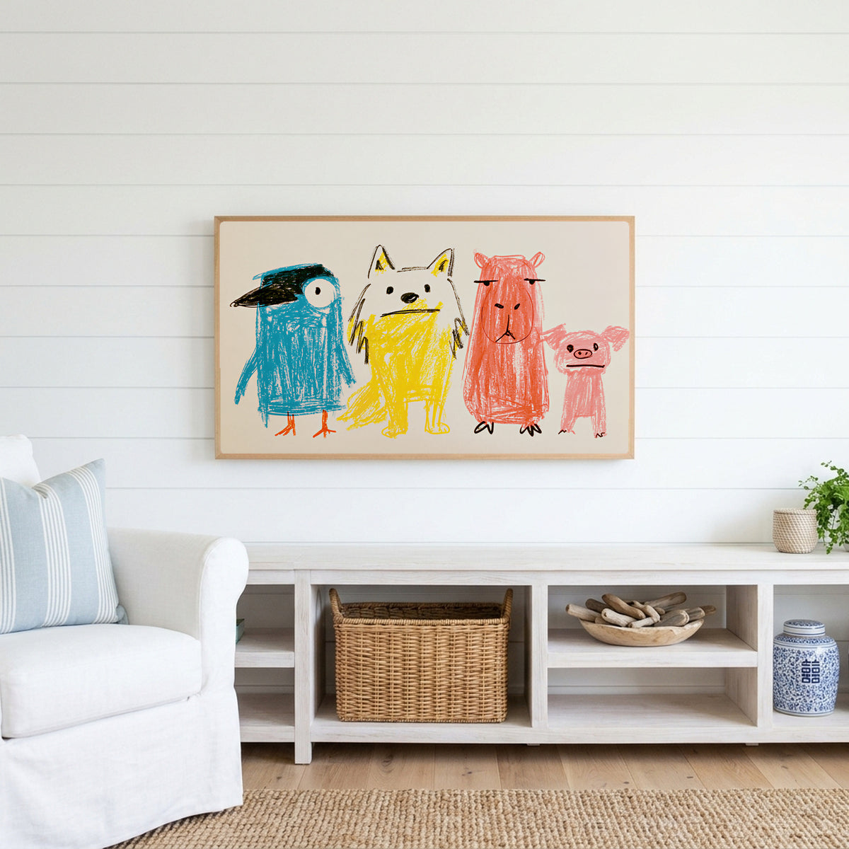 Crayon animals Frame TV art above a white console with a rattan basket in a coastal living room