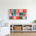 Painted checks Frame TV art above a white console with a rattan basket in a coastal living room