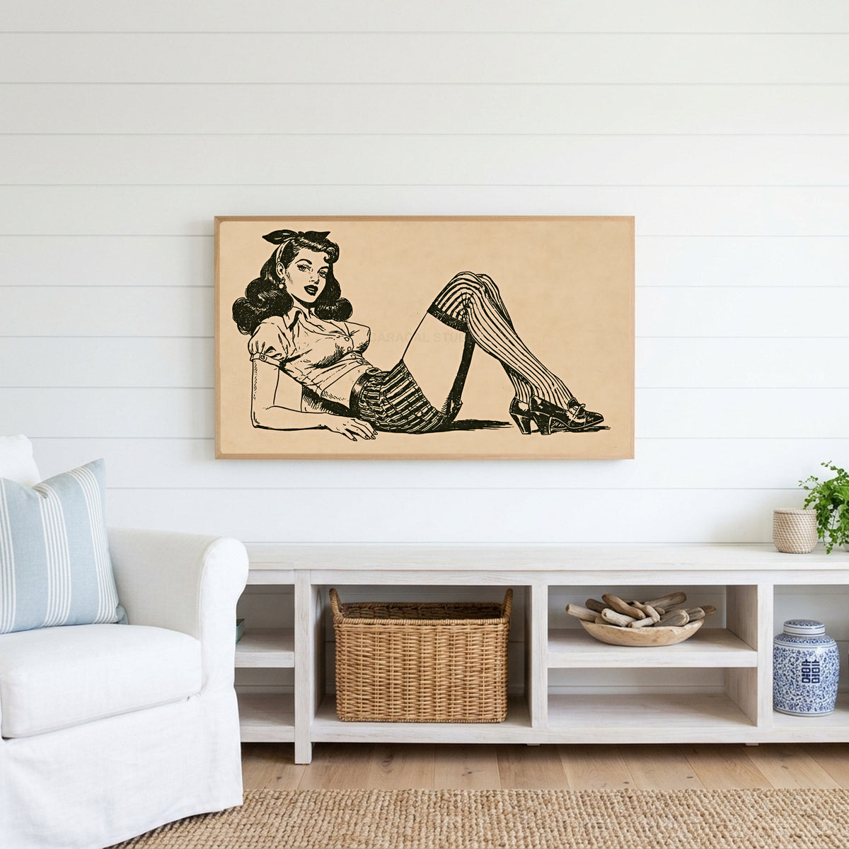 Vintage pin-up drawing Frame TV art above a white console with a rattan basket in a coastal living room