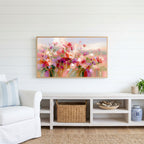 Pink wildflower meadow Frame TV art above a white console with a rattan basket in a coastal living room