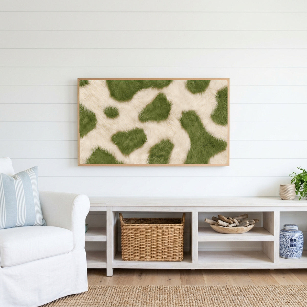 Olive cowhide Frame TV art above a white console with a rattan basket in a coastal living room