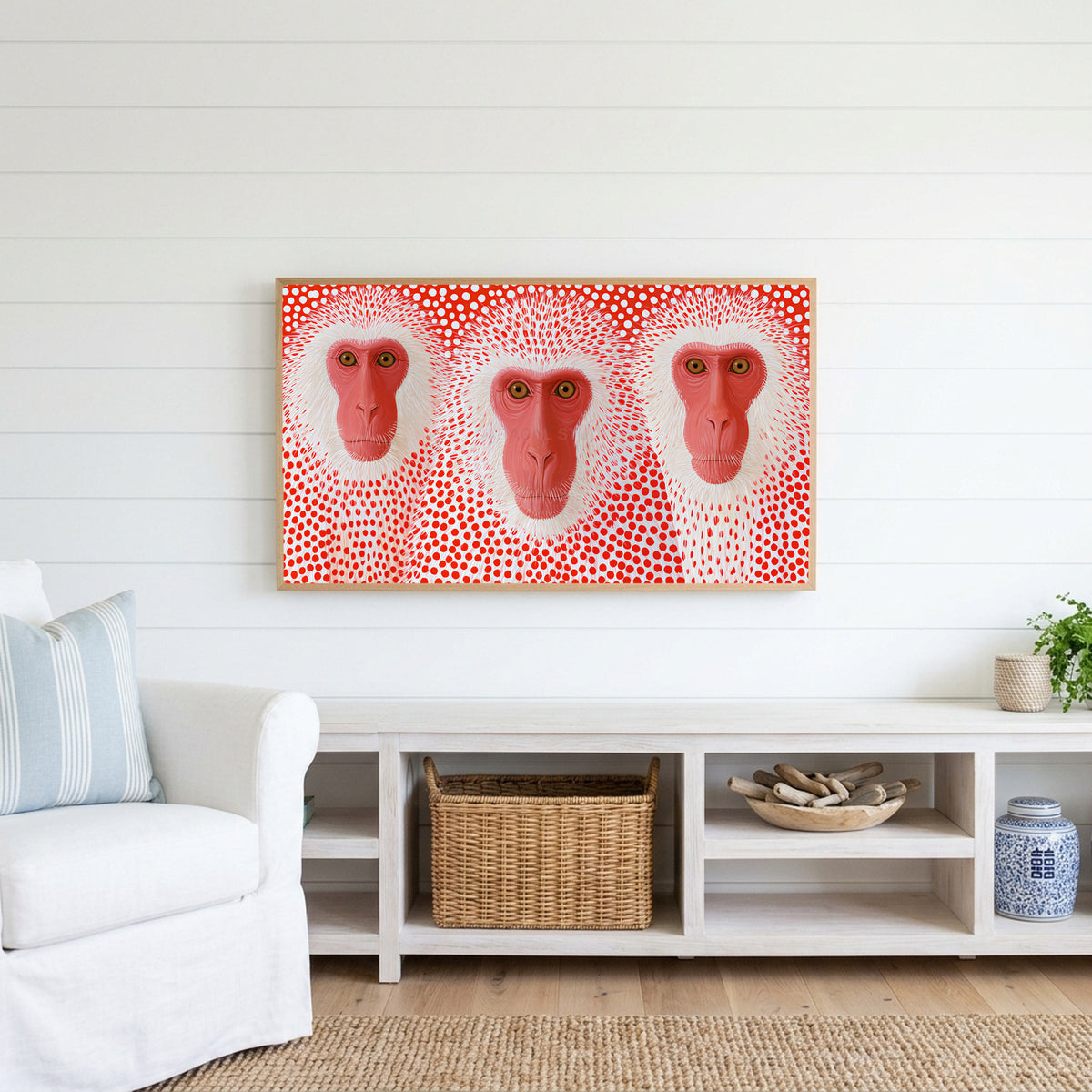 Snow monkeys with red dots Frame TV art above a white console with a rattan basket in a coastal living room
