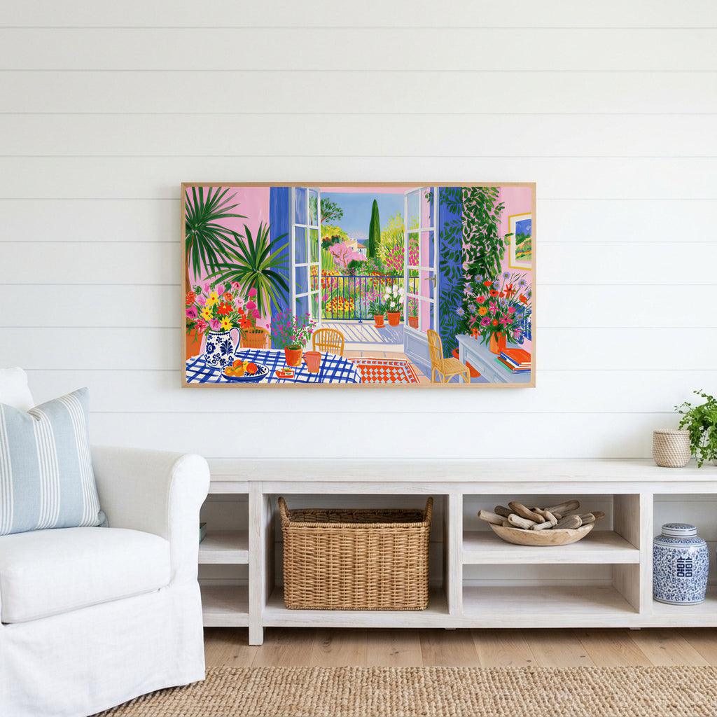 Mediterranean garden view Frame TV art above a white console with a rattan basket in a coastal living room
