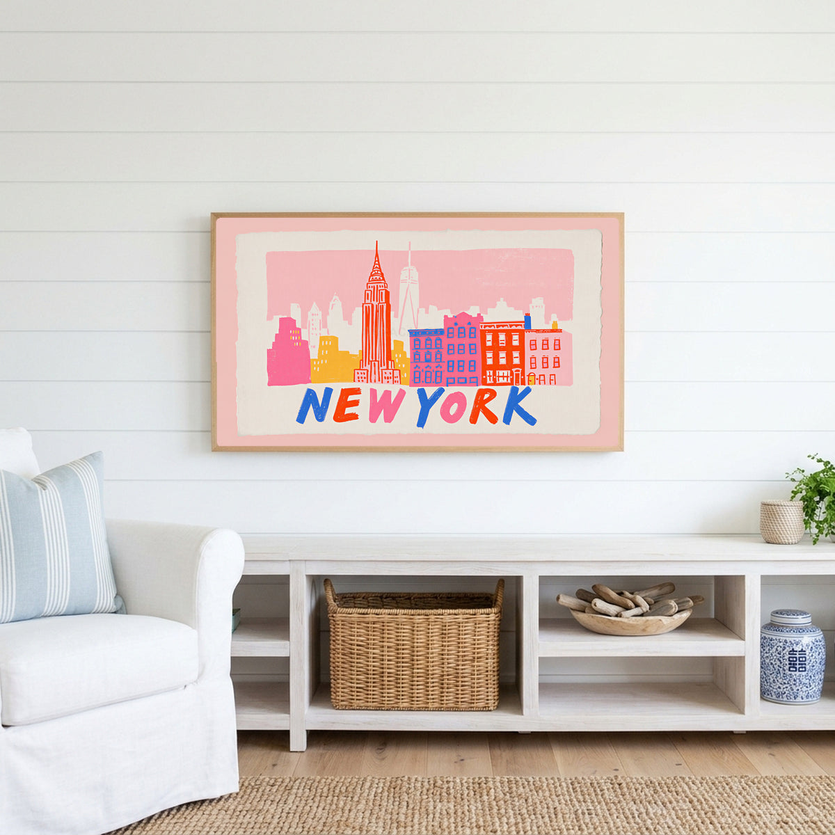 New York skyline Frame TV art above a white console with a rattan basket in a coastal living room