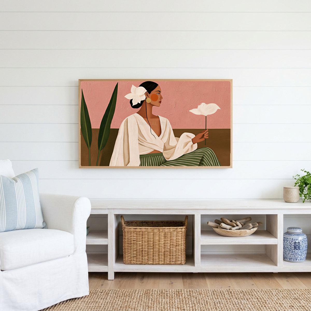 Woman with white flower Frame TV art above a white console with a rattan basket in a coastal living room